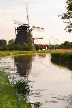 Dutch windmills with reflection after sunrise in spring - vertical