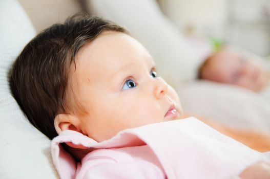 Beautiful cute baby girl is lying in a bed.