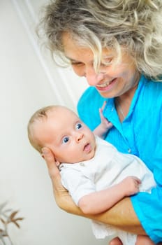 Happy cute infant boy lying on his grandmother hands