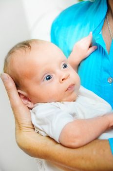 Happy cute infant boy lying on his grandmother hands