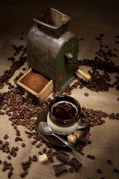 Old coffee mill and cup of coffee with chocolate