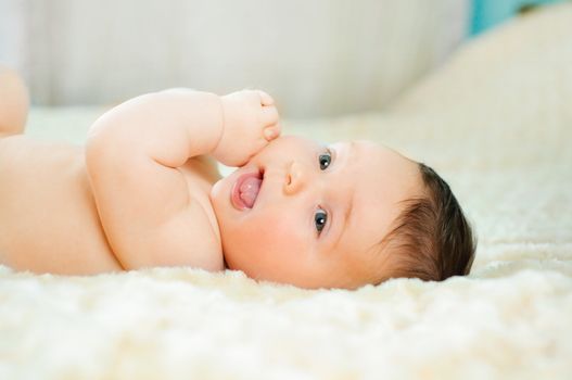 Beautiful cute baby boy is lying in a bed.