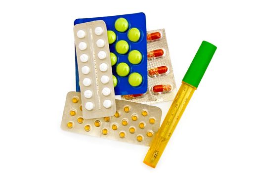 Thermometer in a case with multi-colored capsules and tablets in containers on a white background