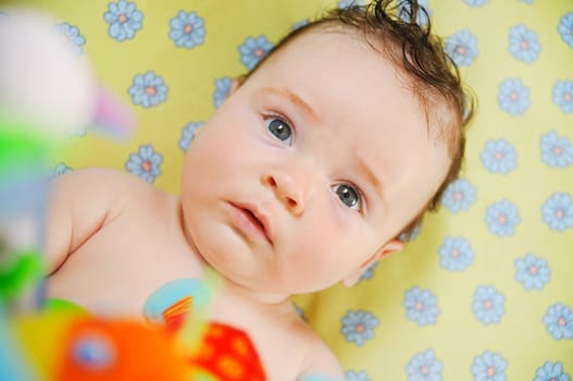 Beautiful cute baby boy is lying in a bed.