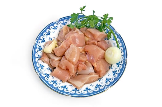 Chicken fillet, cut into large chunks on a plate with onions and parsley