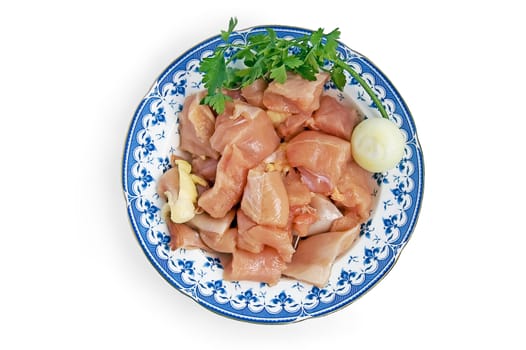 Chicken fillet, cut into large chunks on a plate with onions and parsley isolated on a white background
