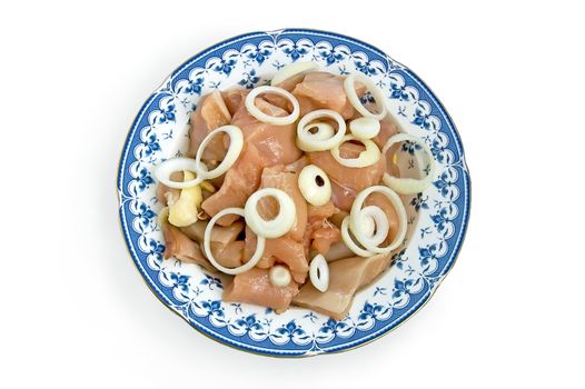 Chicken fillet, cut into large pieces on a plate with onion slices