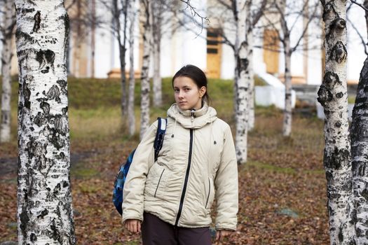 Schoolgirl with a backpack in the autumn park