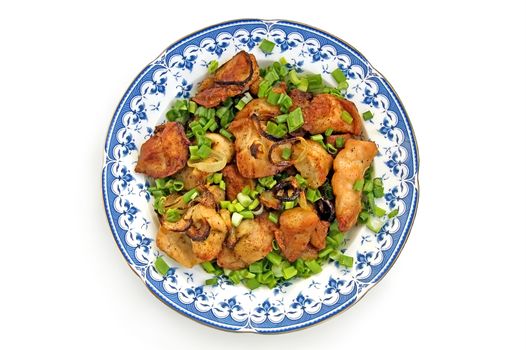 Chunks of roasted chicken with green onion in a dish is isolated on a white background