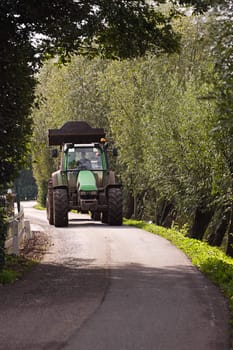 Tractor driving on small country road on sunny summerday