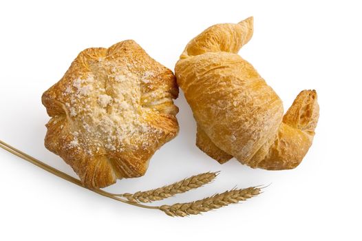 Croissant and bread roll with stalks of wheat in isolation on a white background