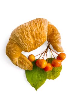 Croissant with a sprig of wild apples and green leaves isolated on white background