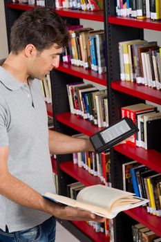 Guy in a library having the choice between e-book and traditional one