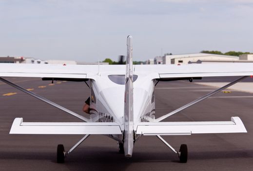 Rear view of small private airplane taxi down the runway with an arm hanging out of the door