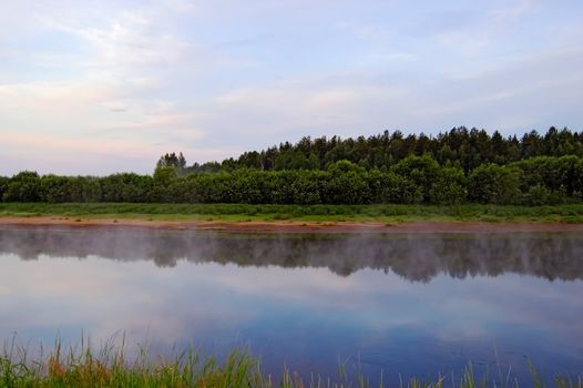 A beautiful sunrise on the river Sosva in the Northern Urals, clouds, painted in red, orange, forest, coast and their reflection in the river