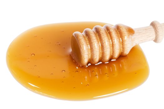 honey dipper from slightly top in a puddle of honey on white background