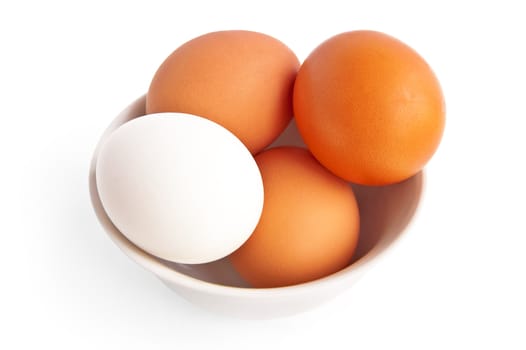 One white and three brown eggs in a bowl is isolated on a white background