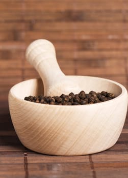 peppercorns in a wooden mortar on wooden background