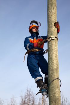 Electrician on the post against the blue sky