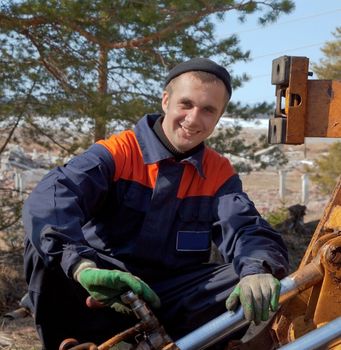 Machinist excavator with a wrench in his hand repairing a tractor