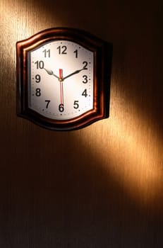 Clock hanging on wooden wall with beam of light