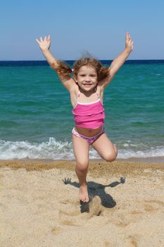 happy little girl jumping on the beach
