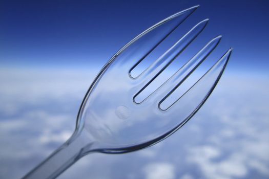 Clear plastic disposable fork against the sky