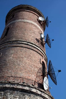 Modern communications antenna on an old tower against the blue sky