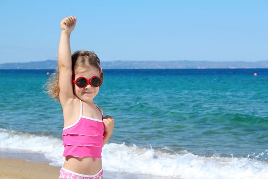 little girl with hand up posing on beach