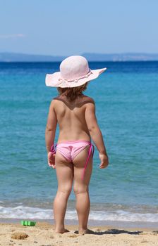 little girl with straw hat looking at sea