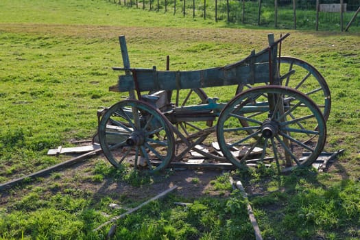 Old four wheel wooden horse cart on a field slowly falling to pieces