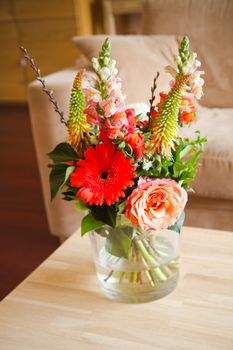 Bouguet of flowers in glass vase on table in modern interior with shallow dof