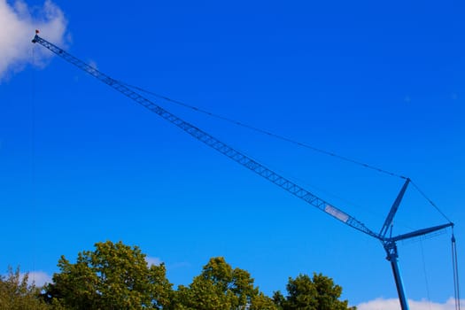 Huge crane above trees with blue sky