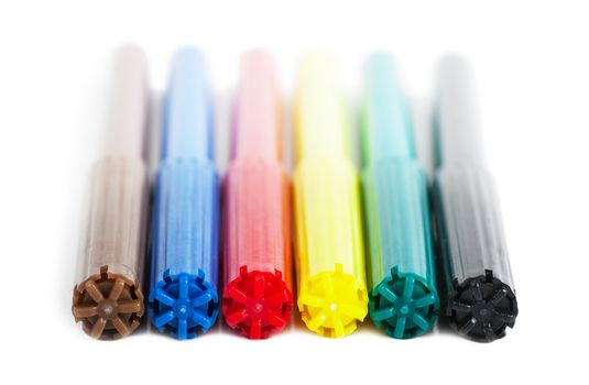 Six colorful markers (brown, blue, red, yellow, green and black) over white background