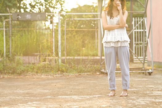 Asian woman standing and thinking in basketball court, half body image, let people have more imagination.