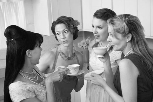 Four retro-styled women chit-chat over coffee in a kitchen