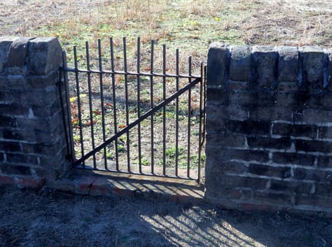 An iron gate in a brick wall enclosure around the family cemetary at historic Garthright House in Hanover County, Virginia. During the civil war the house was used as a military hospital while the family hid in the basement.