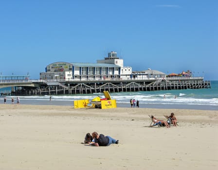 A view of a beach, sea and a pier.