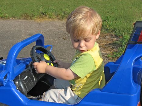 The nice little boy operates car-toy. Summer