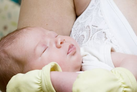 Newborn sleeping child in the hands of mother