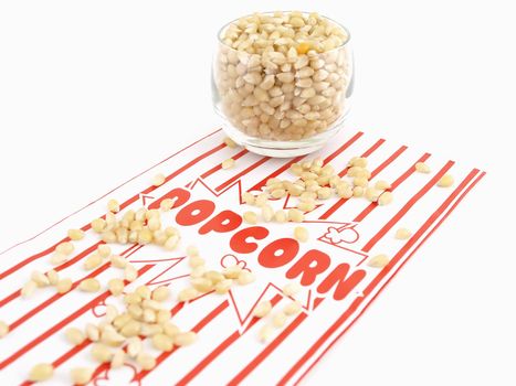 A popcorn bag and kernels isolated over a white background.