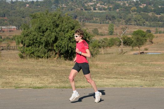 Female athlete running in red clothing.