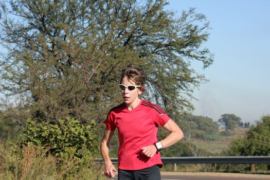 Female athlete running dressed in red.