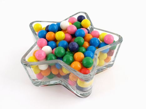 A star shaped dish filled with multi colored gumballs isolated over a white background.