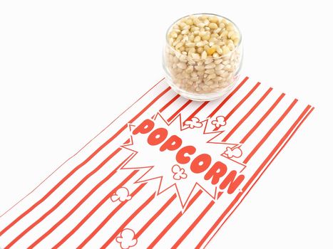 A red and white popcorn box with a glass dish full of unpopped kernels