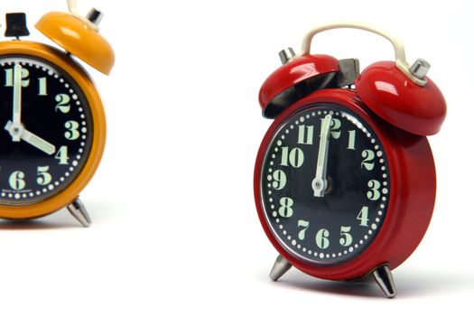 red and orange color alarm clock at twelve oclock isolated on white background