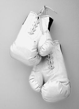 White boxe gloves pending from a nail on a wall