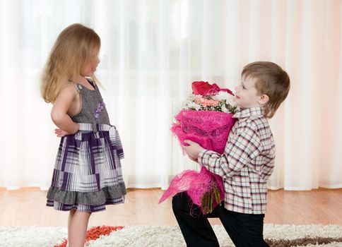 The little boy gives to the girl a bunch of flowers