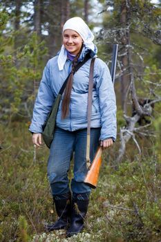 Girl with a shotgun in the autumn forest