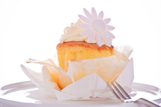 Cupcake with vanilla cream and sugar flower on a white background